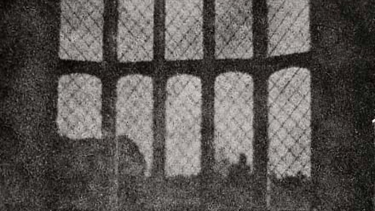 A black and white print taken from the earliest 'photogenic drawing' by Henry Fox Talbot, showing the lattice window from Lacock Abbey's South Gallery in full frame.